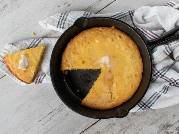 ovenfra av maisbrød i en jerngryte med ett stykke fjernet