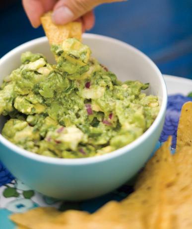 Guacamole og chips servert på et fat.