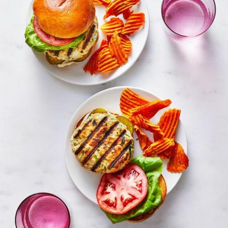 Åpen grillet kalkun-zucchini burgere med chips på siden på en hvit tallerken